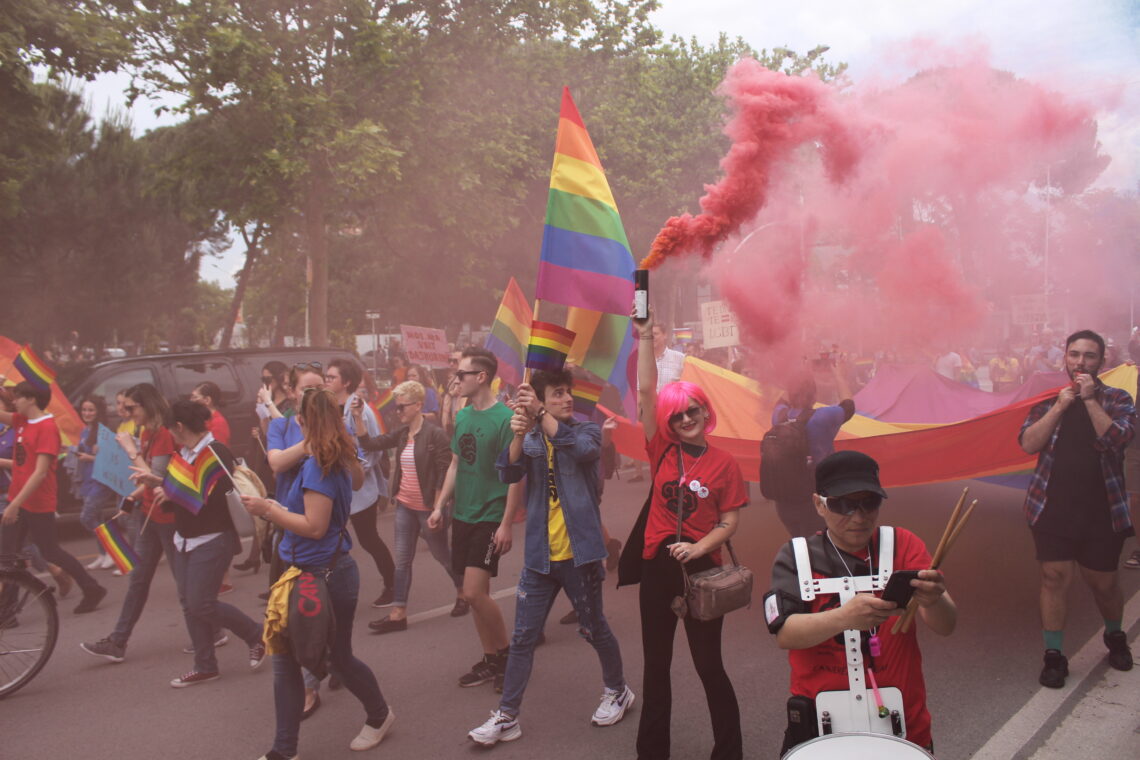 Pride parade marchers with Rainbow flags and pink smoke